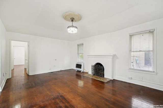 unfurnished living room with heating unit and dark hardwood / wood-style flooring