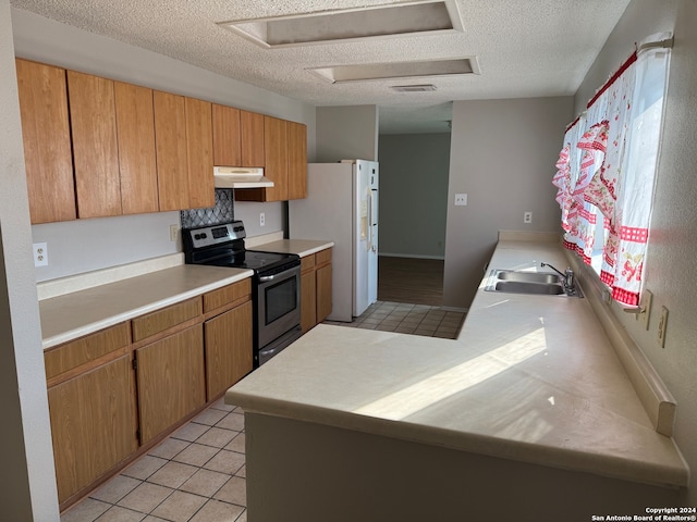 kitchen with stainless steel electric stove, sink, light tile patterned flooring, white refrigerator with ice dispenser, and a textured ceiling