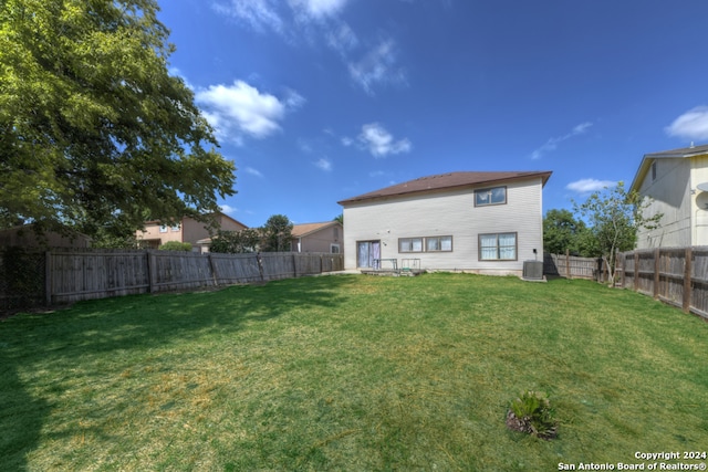 back of property featuring a yard and central AC