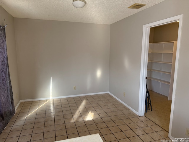 tiled empty room featuring a textured ceiling