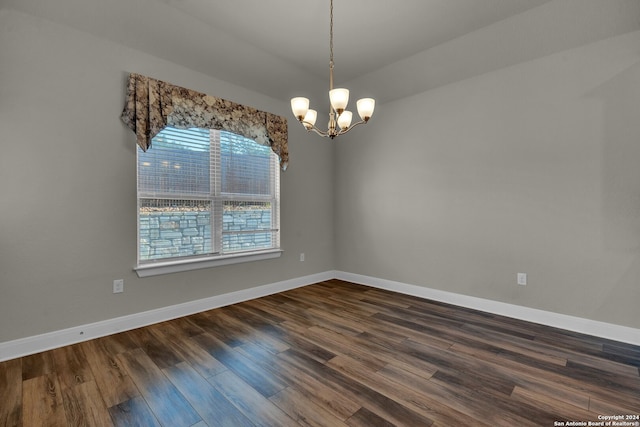 spare room with dark hardwood / wood-style floors and a chandelier