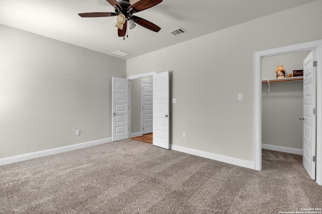 unfurnished bedroom with ceiling fan, a spacious closet, carpet floors, and a closet