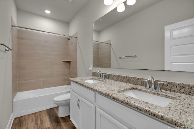 full bathroom with vanity, wood-type flooring, tiled shower / bath combo, and toilet