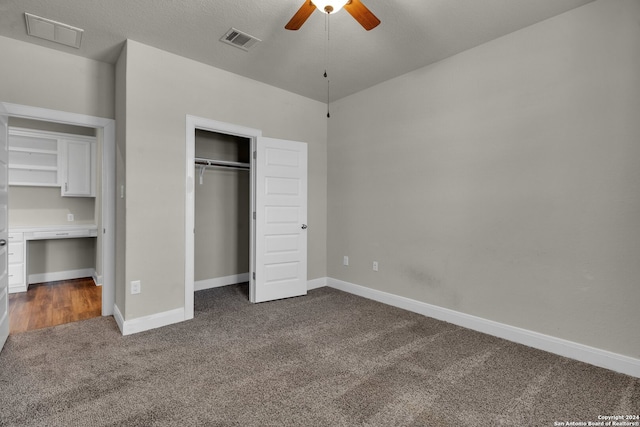 unfurnished bedroom with ceiling fan, dark carpet, and a textured ceiling