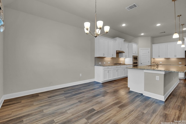 kitchen with dark hardwood / wood-style floors, an island with sink, decorative light fixtures, white cabinetry, and stainless steel appliances