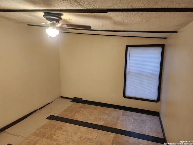 tiled empty room with ceiling fan and a textured ceiling