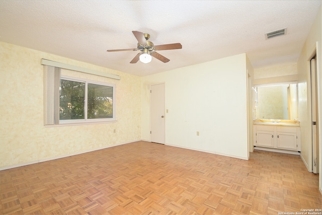 spare room with sink, ceiling fan, light parquet flooring, and a textured ceiling