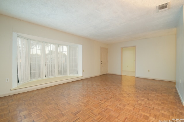 unfurnished room with light parquet flooring and a textured ceiling