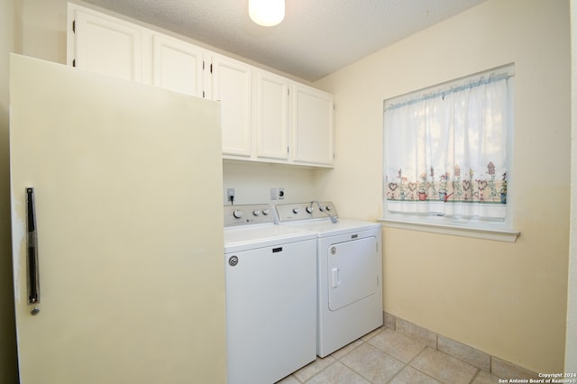 laundry room with washing machine and dryer, a textured ceiling, light tile patterned flooring, and cabinets