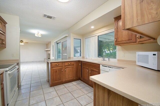 kitchen with ceiling fan, white appliances, sink, kitchen peninsula, and light tile patterned floors