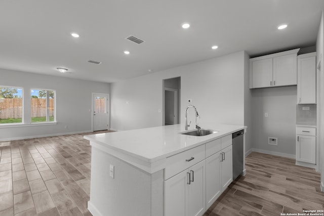 kitchen with light hardwood / wood-style flooring, a center island with sink, sink, white cabinets, and stainless steel dishwasher