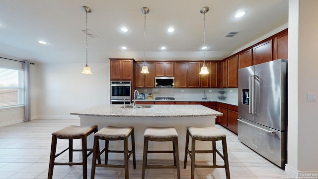 kitchen featuring hanging light fixtures, sink, a center island with sink, stainless steel appliances, and a breakfast bar area