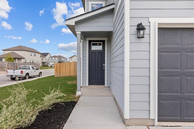 view of exterior entry with a garage and a yard