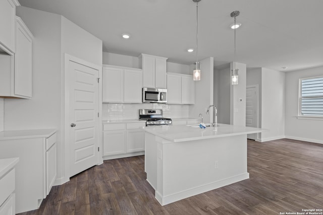 kitchen with white cabinets, a kitchen island with sink, decorative light fixtures, appliances with stainless steel finishes, and dark hardwood / wood-style floors