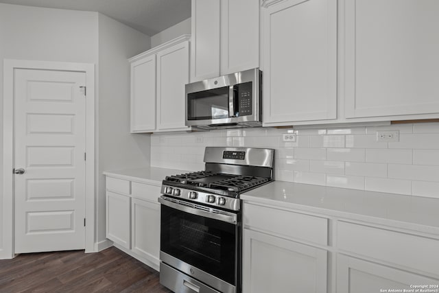 kitchen featuring appliances with stainless steel finishes, decorative backsplash, white cabinetry, and dark hardwood / wood-style floors