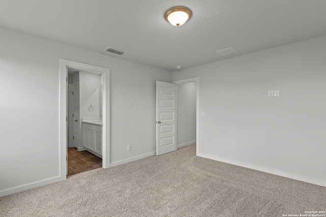 unfurnished bedroom featuring dark colored carpet and ensuite bathroom