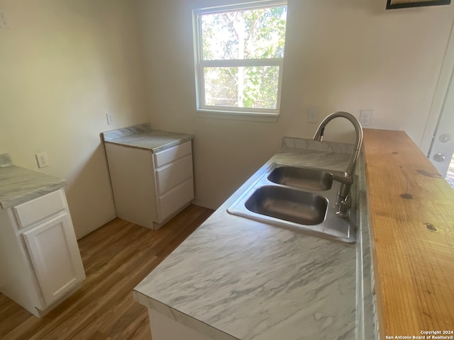 kitchen featuring light wood-type flooring, sink, and white cabinetry