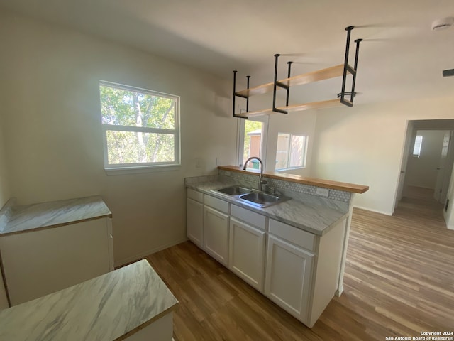 kitchen with white cabinets, light hardwood / wood-style floors, sink, and kitchen peninsula