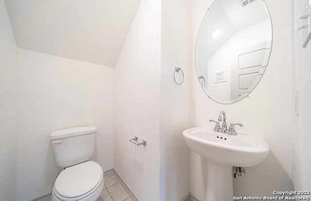 bathroom featuring lofted ceiling, tile patterned flooring, and toilet