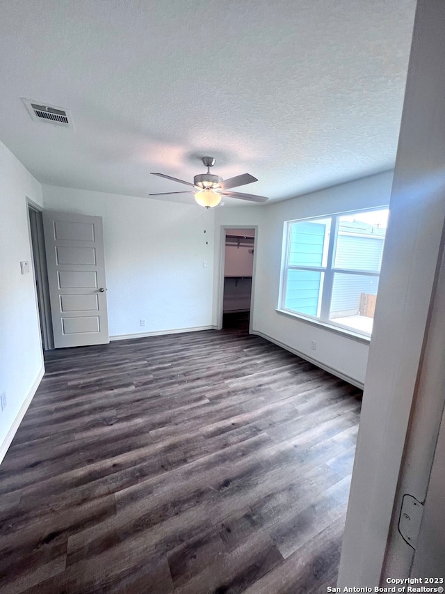 unfurnished bedroom with dark hardwood / wood-style flooring, a textured ceiling, and ceiling fan