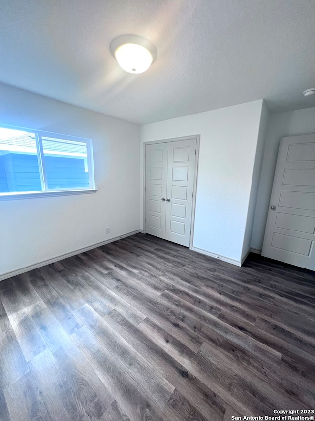 unfurnished room with a textured ceiling and dark hardwood / wood-style flooring