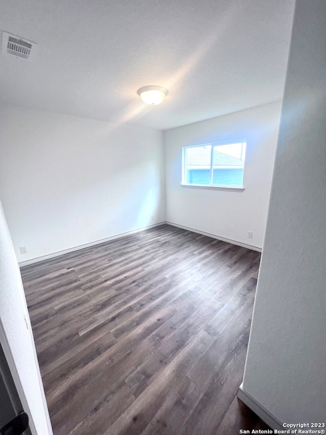 unfurnished room with dark wood-type flooring