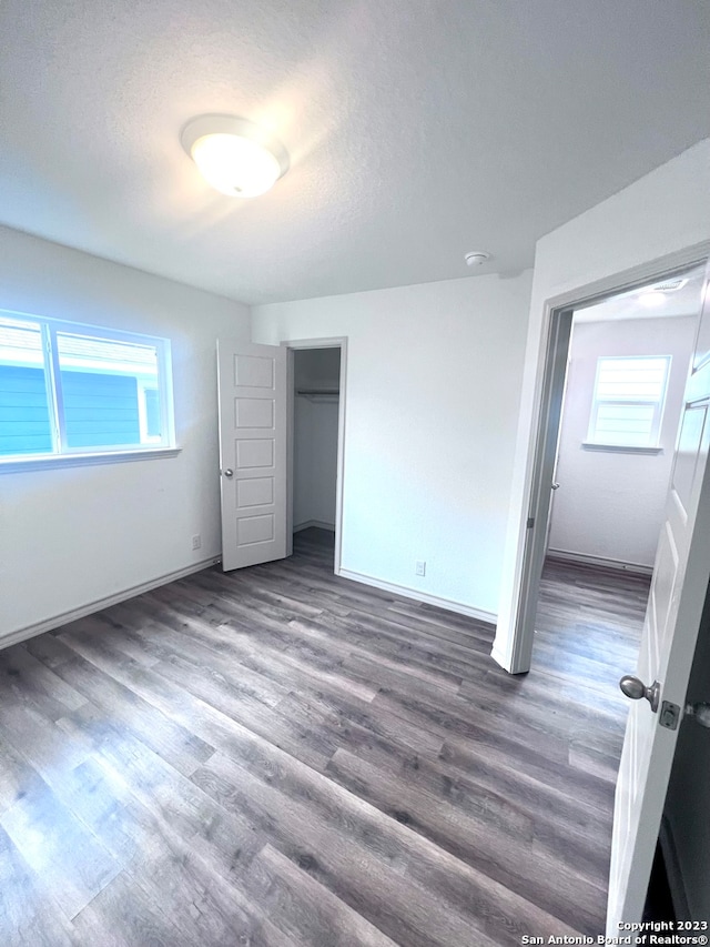 unfurnished bedroom featuring dark hardwood / wood-style flooring, multiple windows, and a textured ceiling