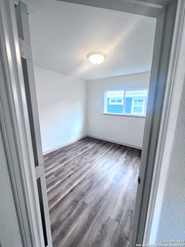 spare room with dark hardwood / wood-style flooring and a textured ceiling