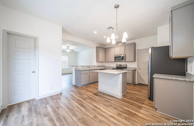 kitchen with pendant lighting, a kitchen island, gray cabinets, appliances with stainless steel finishes, and light wood-type flooring