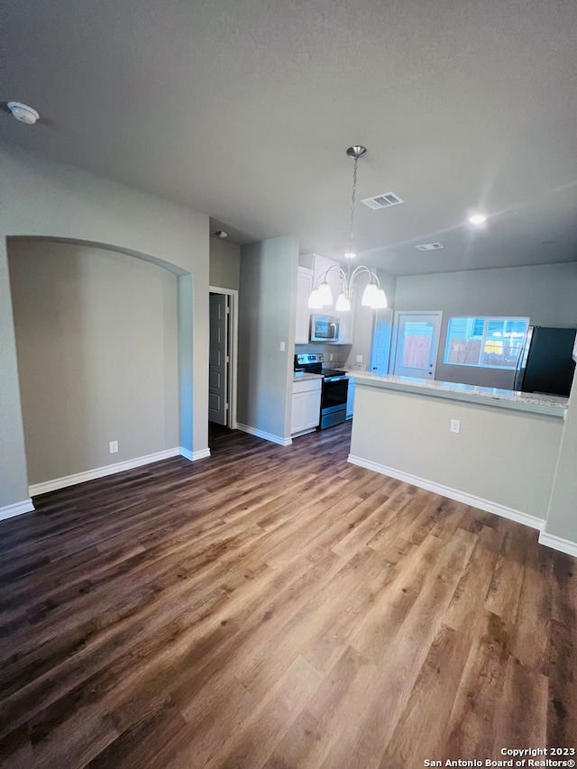 unfurnished living room featuring a notable chandelier, wood-type flooring, and a textured ceiling