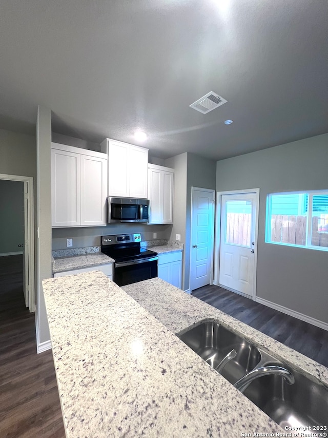 kitchen featuring white cabinetry, light stone counters, stainless steel appliances, and dark hardwood / wood-style flooring