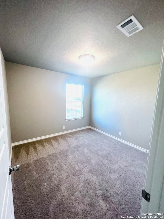 carpeted empty room featuring a textured ceiling