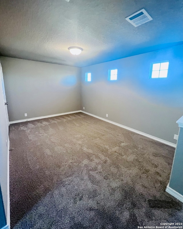 carpeted empty room with a textured ceiling