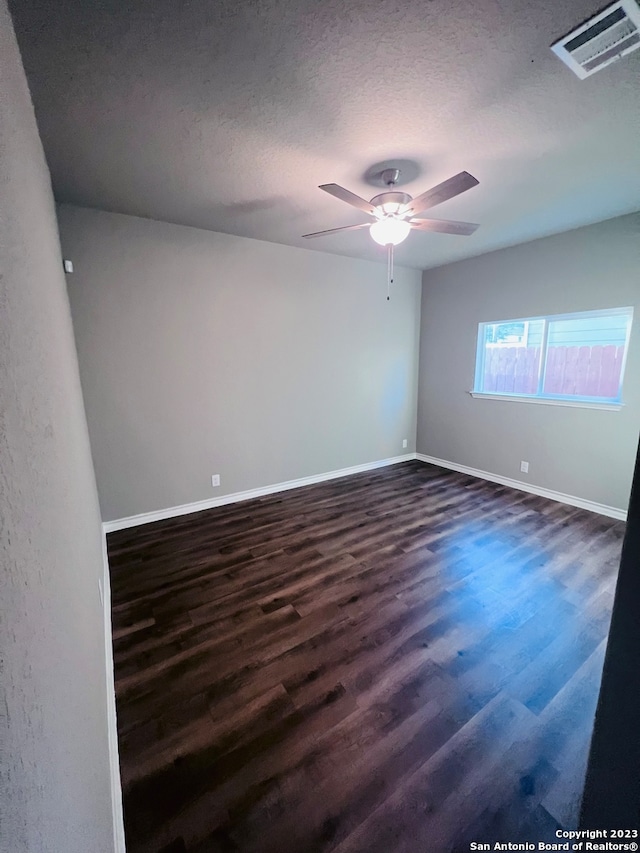 empty room featuring ceiling fan, a textured ceiling, and dark hardwood / wood-style floors