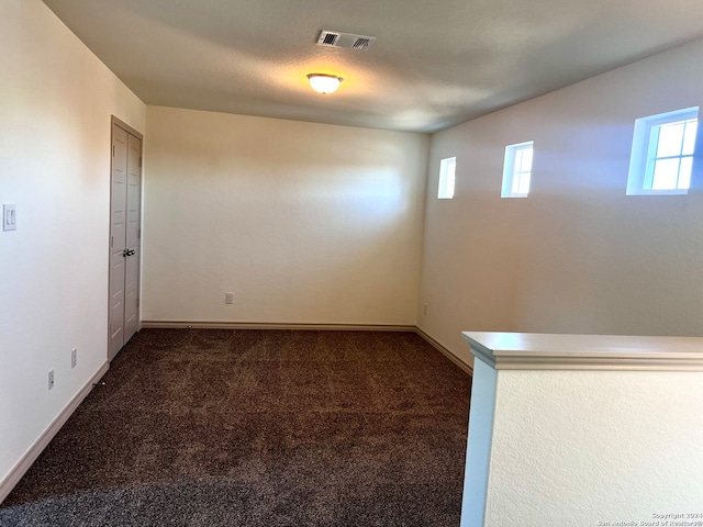 carpeted empty room with a wealth of natural light and a textured ceiling