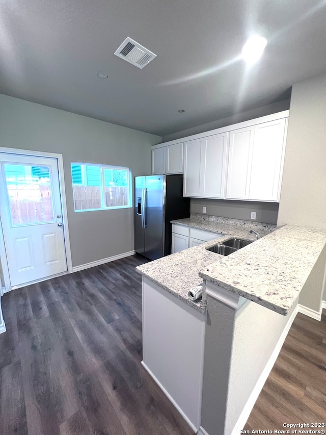 kitchen featuring dark wood-type flooring, kitchen peninsula, stainless steel fridge, sink, and white cabinets