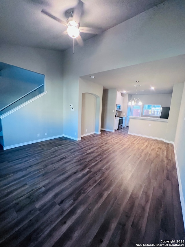 unfurnished living room with dark wood-type flooring and ceiling fan with notable chandelier