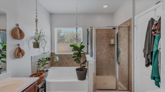 bathroom with vanity and shower with separate bathtub