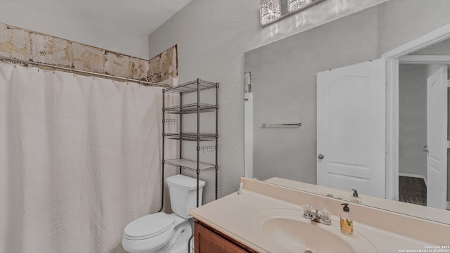 bathroom featuring walk in shower, vanity, and toilet