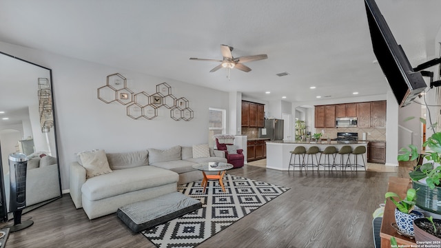 living room featuring ceiling fan and dark hardwood / wood-style floors