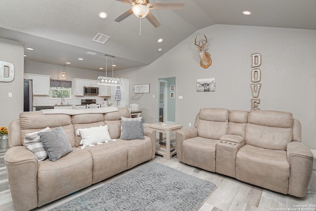 living room featuring ceiling fan, vaulted ceiling, sink, and light hardwood / wood-style floors