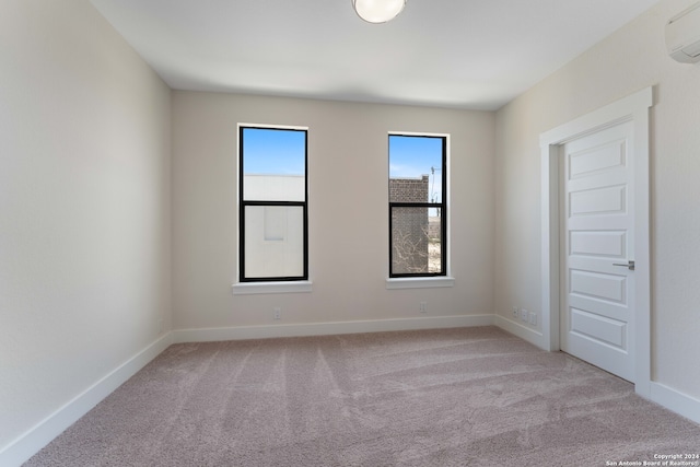 spare room featuring a wall mounted air conditioner and light colored carpet