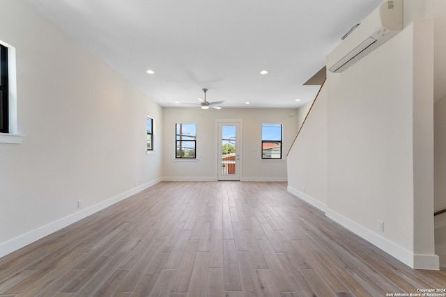 unfurnished living room featuring light hardwood / wood-style floors, ceiling fan, and a wall mounted AC