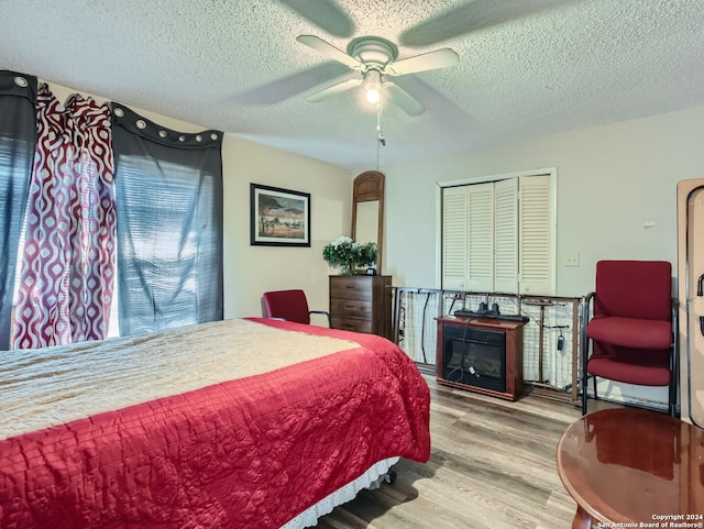 bedroom with ceiling fan, a textured ceiling, light wood-type flooring, and a closet