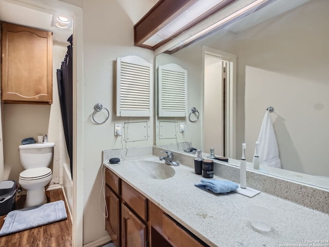 full bathroom with hardwood / wood-style floors, vanity, shower / bath combo with shower curtain, and toilet