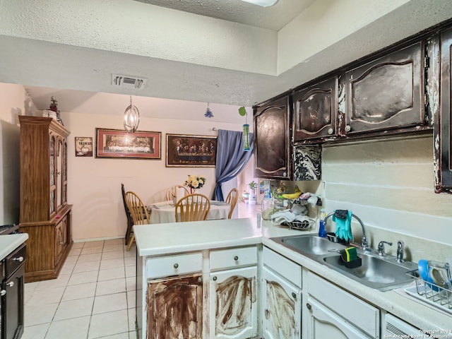 kitchen featuring light tile patterned flooring, kitchen peninsula, hanging light fixtures, and sink