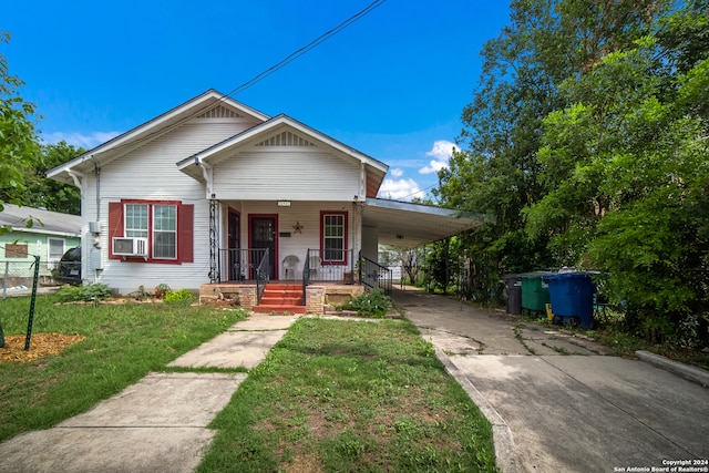 bungalow-style home featuring a carport, covered porch, and a front yard