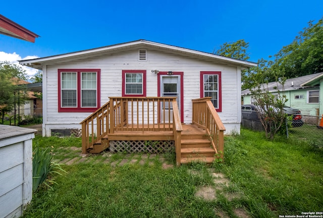 rear view of property with a wooden deck and a yard