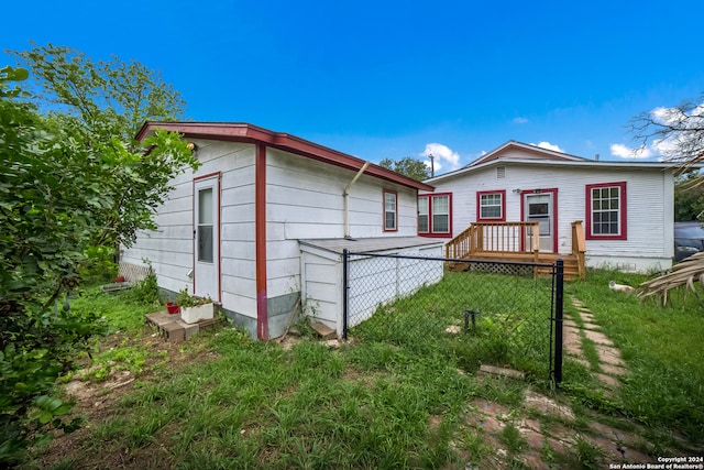 rear view of house with a yard and a wooden deck