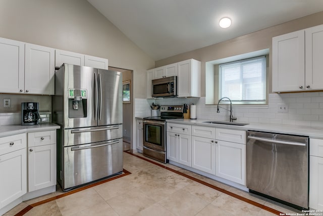 kitchen with vaulted ceiling, sink, backsplash, white cabinets, and appliances with stainless steel finishes